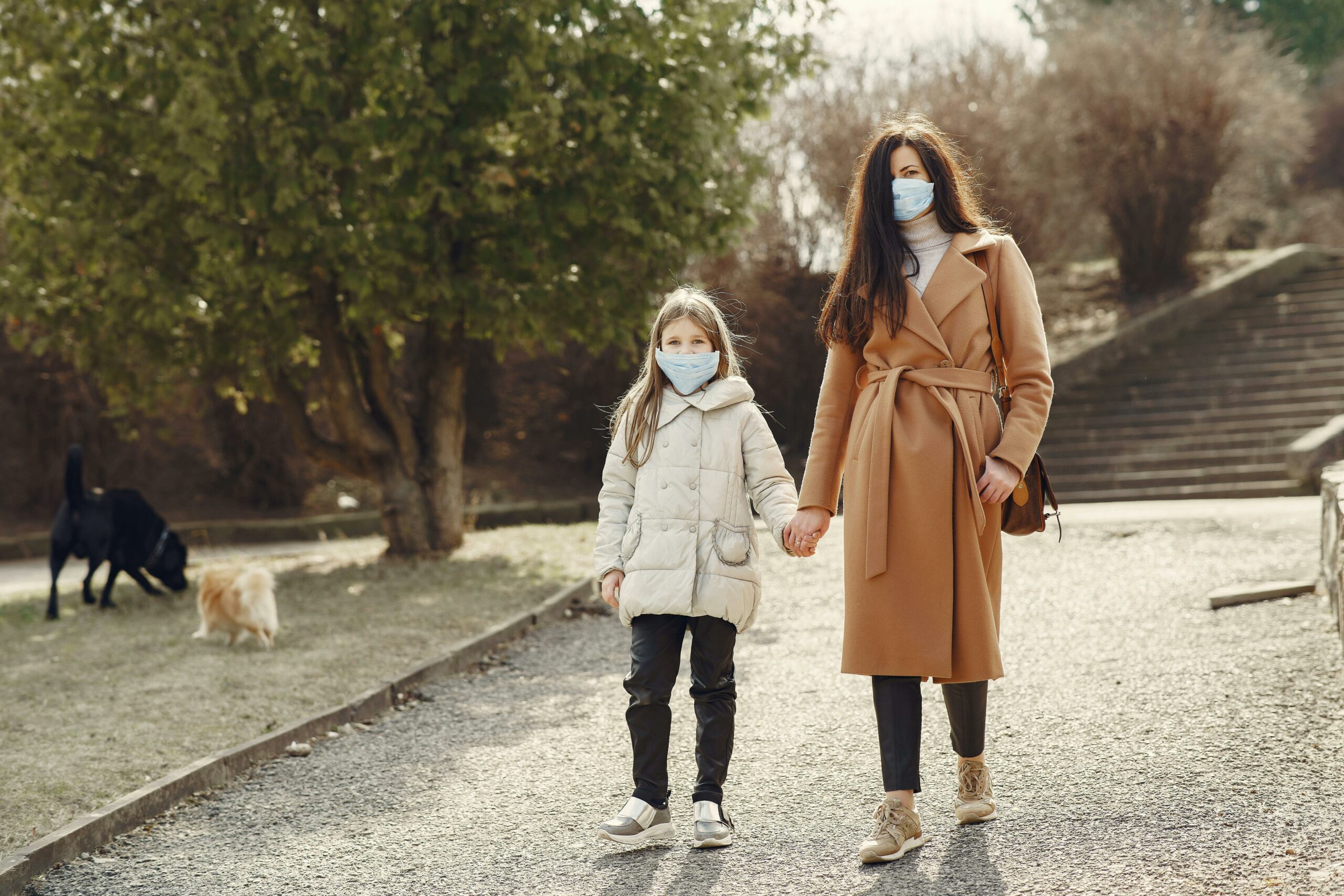 Mutter Mit Tochter In Gesichtsmasken, Die Im Park Gehen